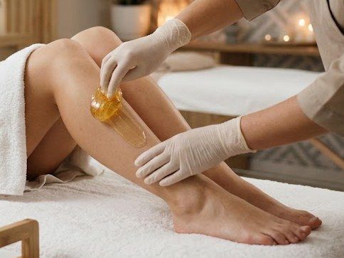 Esteticista aplicando cera con espátula en la pierna, depilación con cera en KALON