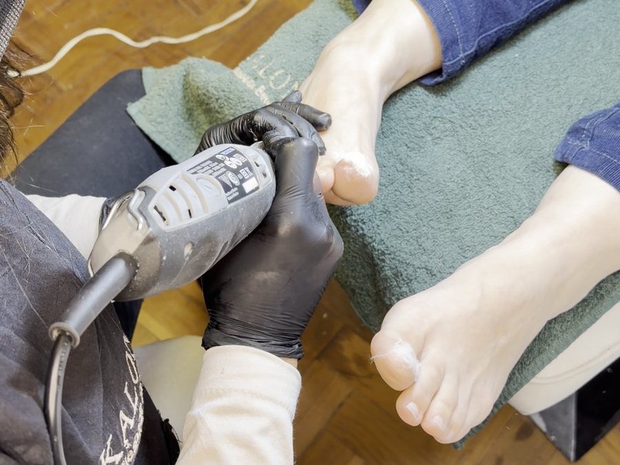 Podóloga con guantes tratando durezas del pie con torno en KALON