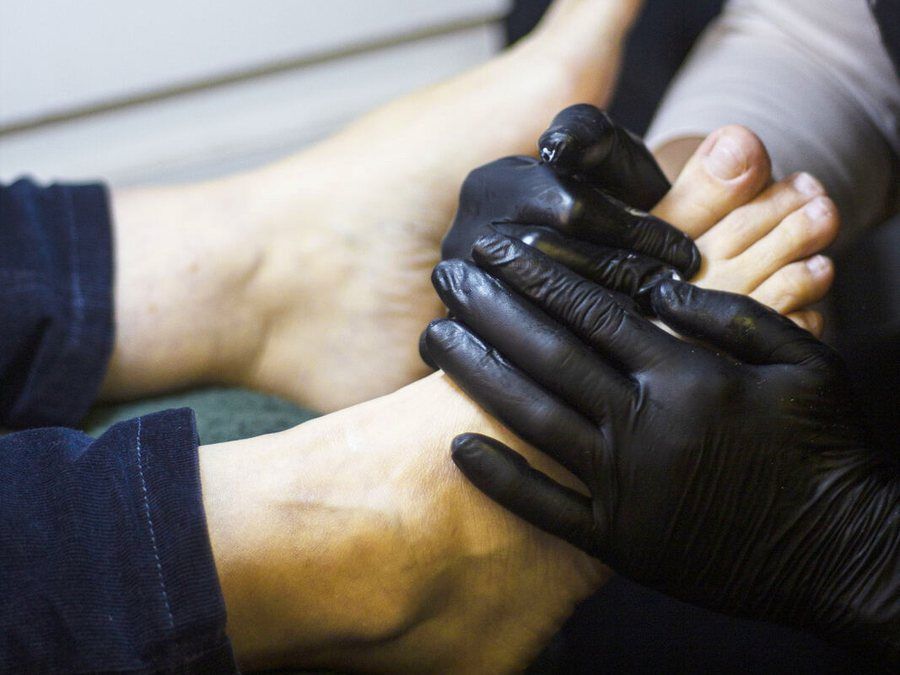 Podóloga con guantes revisando el pie de un paciente, evaluación podológica en KALON