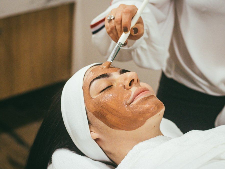 Esteticista aplicando peeling químico con pincel sobre el rostro