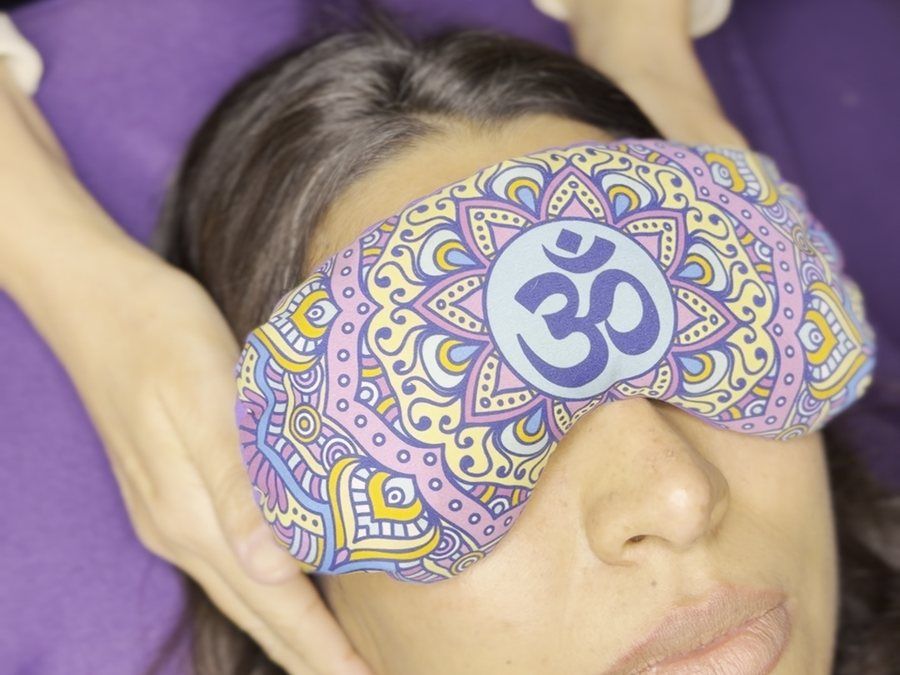 Clienta con antifaz recostada durante una sesión de reiki en KALON