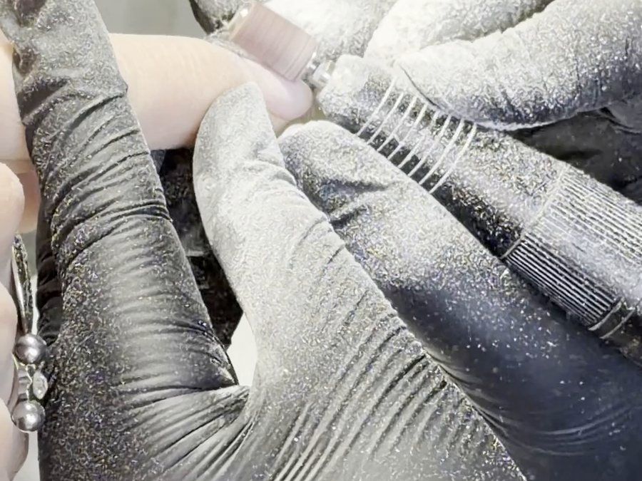 Manicura con guantes retirando el material de las uñas con torno en KALON